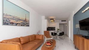 Ein modernes Wohnzimmer mit einer Couch, einem Couchtisch mit Obst, einem Fernseher und einem Stadtbild.