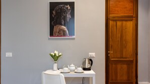 A room with a white table set for tea, a vase with flowers, and a wooden door. - River61 - Guest House (Rome)