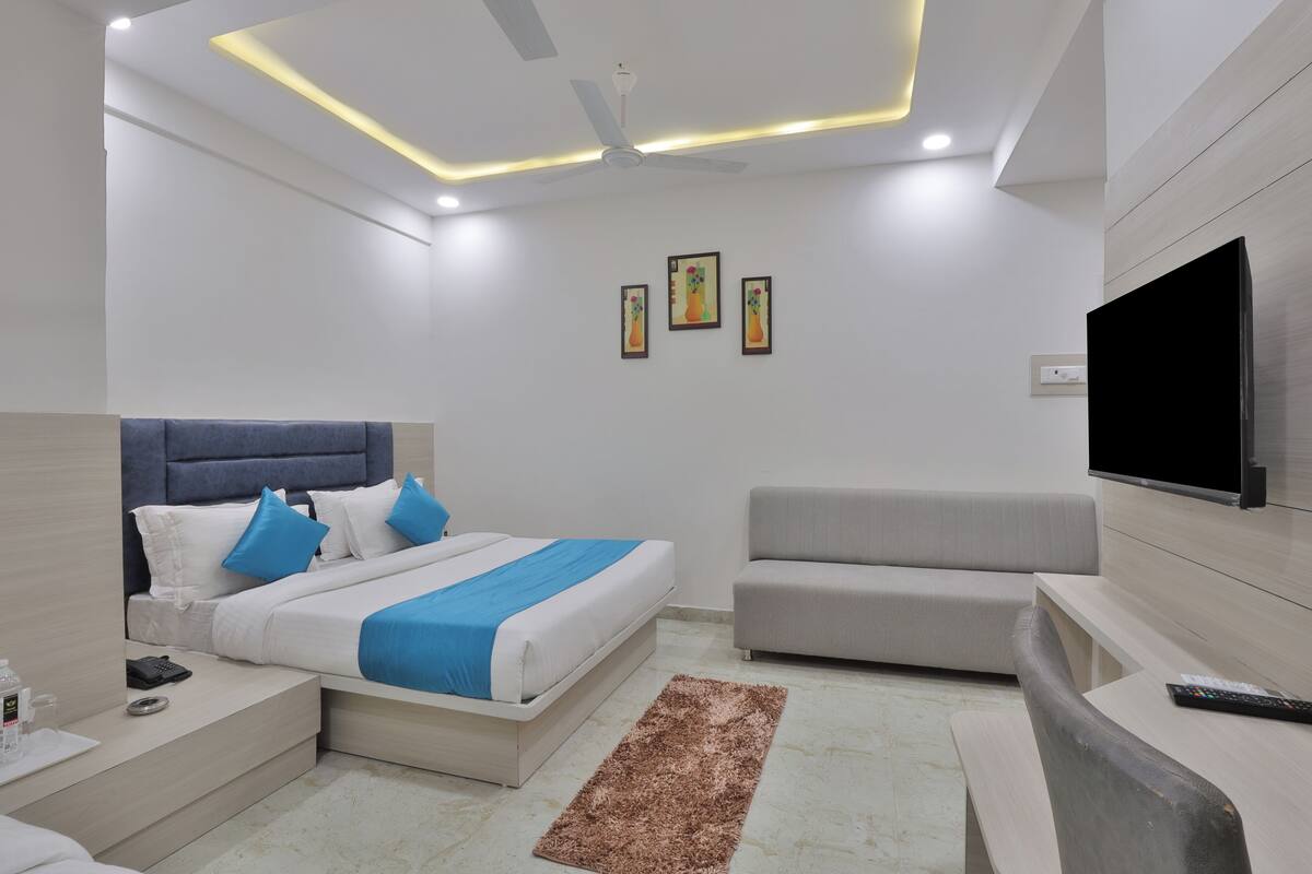 Quarto de hotel moderno com uma cama, um sofá, uma TV e um ventilador de teto.