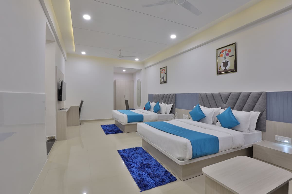 Quarto de hotel moderno com duas camas, televisão, secretária e banheiro.