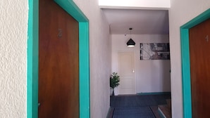 Un pasillo con dos puertas de madera, una puerta blanca y una planta pequeña.