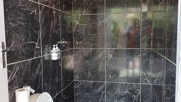 Un baño con inodoro, ducha y secador de manos.