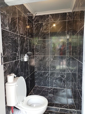 Un baño con inodoro, ducha y secador de manos.