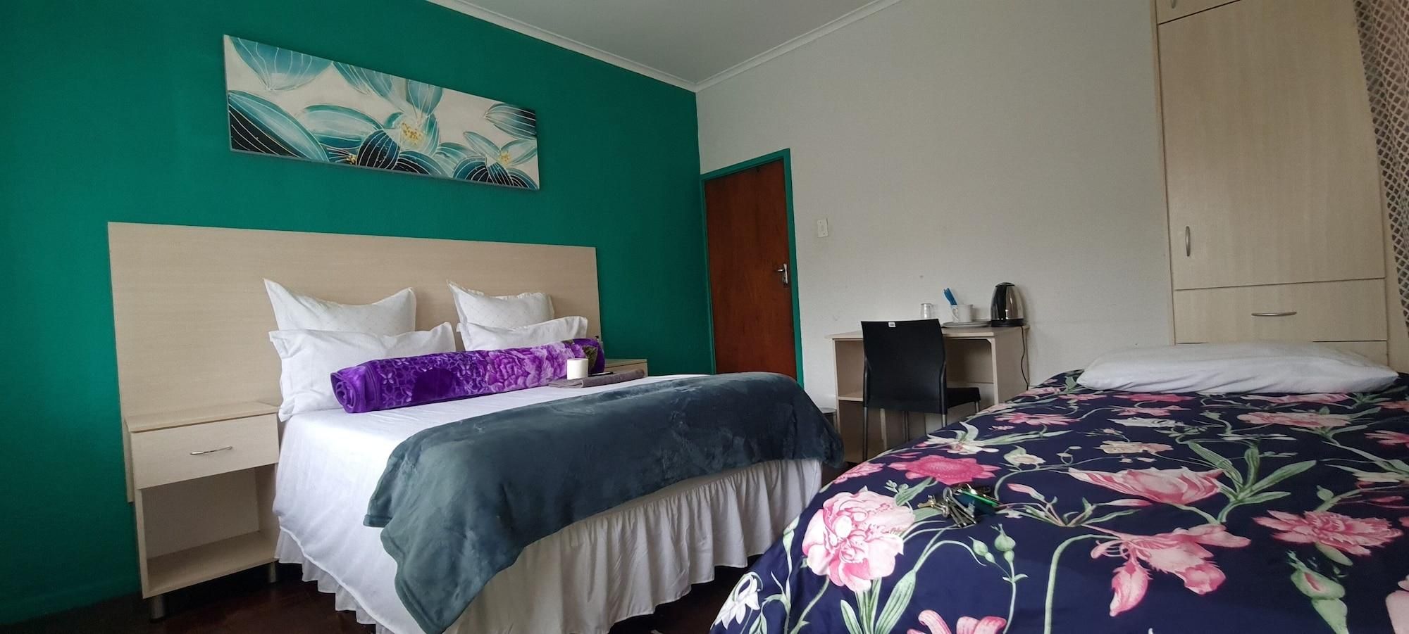 Habitación de hotel con cama, escritorio, silla y un cuadro en la pared.