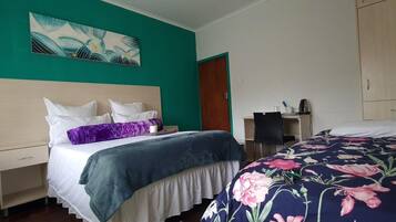 Habitación de hotel con cama, escritorio, silla y un cuadro en la pared.