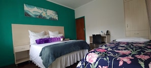 Habitación de hotel con cama, escritorio, silla y un cuadro en la pared.