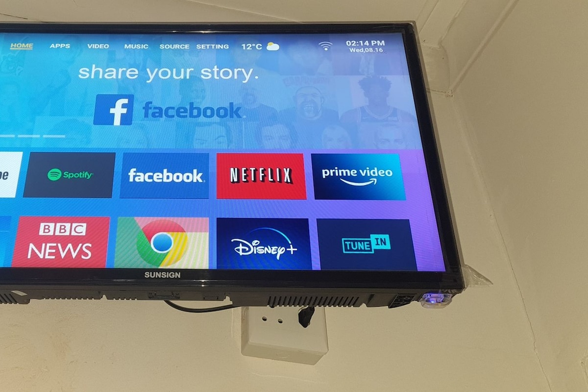 Een flatscreen televisie aan de wand bevestigd, met een interface voor sociale media en streamingdiensten.