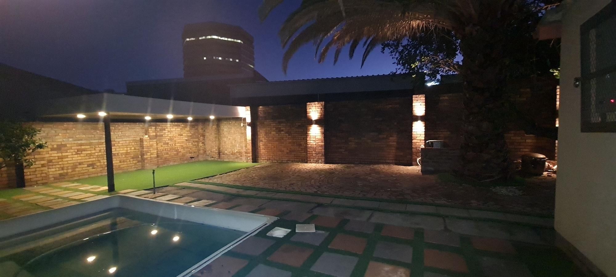 Una piscina, un muro de ladrillo y un edificio iluminado.