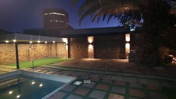 Una piscina, un muro de ladrillo y un edificio iluminado.