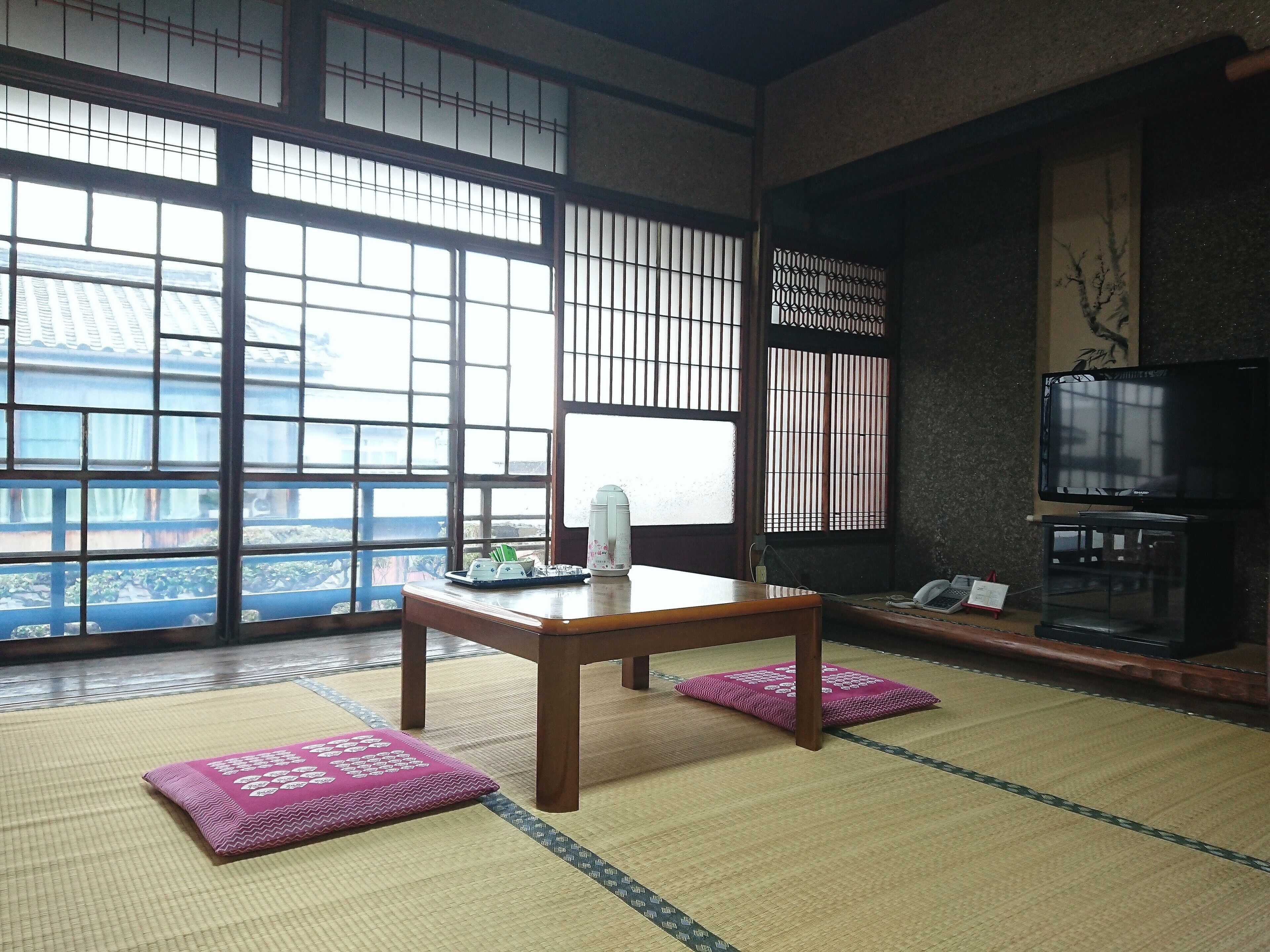 A traditional Japanese room with tatami flooring, a low wooden table, and a television.