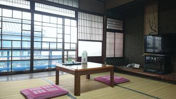 A traditional Japanese room with tatami flooring, a low wooden table, and a television.