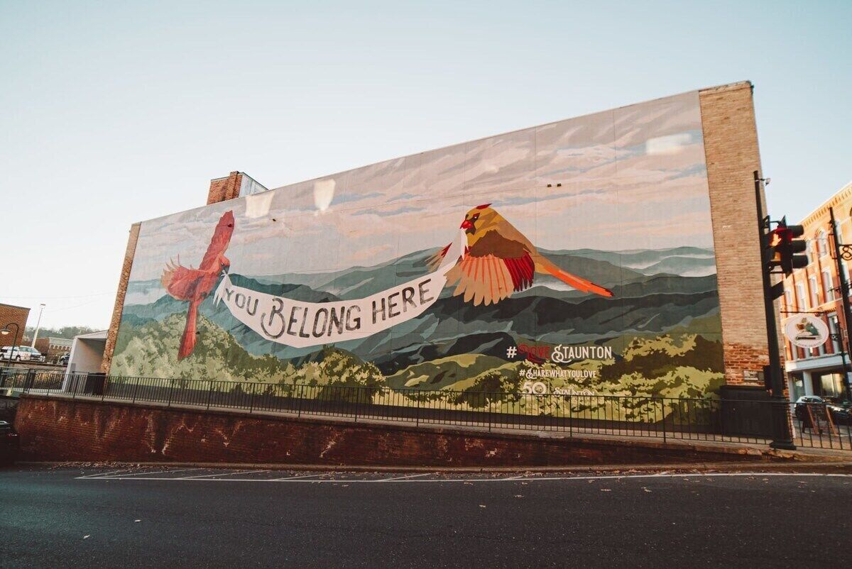 Un mural en un edificio que muestra aves y el texto 'YOU BELONG HERE'.