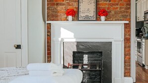 Ein Zimmer mit Kamin, einem Bett mit weißer Bettwäsche und einem gemusterten Teppich.