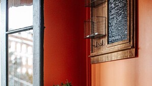 A wooden chair with a patterned cushion, a small table with a plant, and a wall with a chalkboard. - The Shenandoah Suite (Staunton)