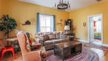 A living room with a sofa, armchair, coffee table, and a chandelier.