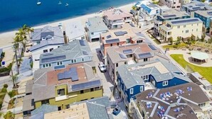 An aerial view of a coastal residential area with houses, a beach, and boats.