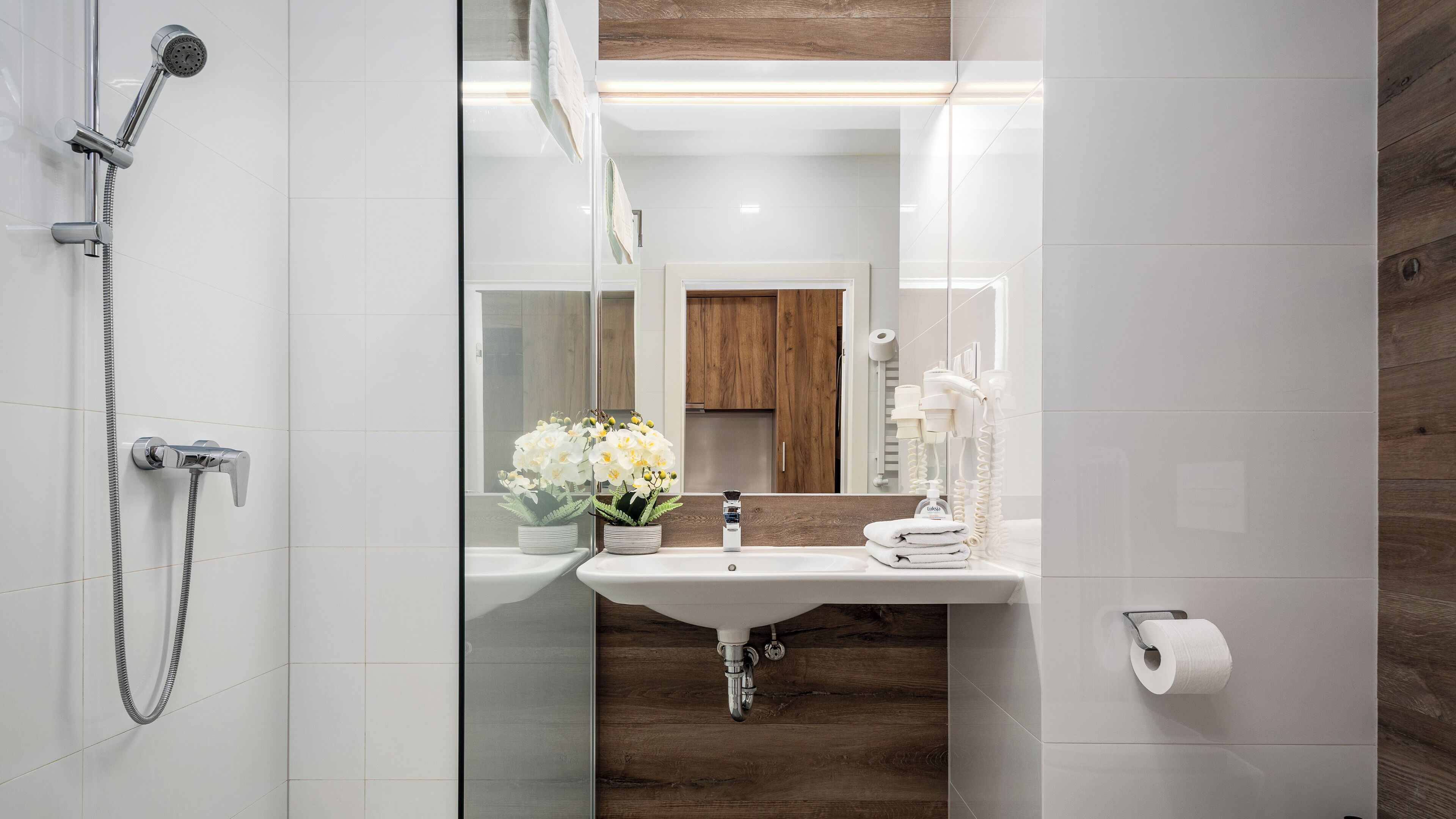 A modern bathroom with a shower, sink, and toilet.