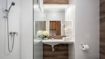 A modern bathroom with a shower, sink, and toilet.