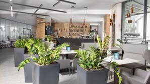 A modern hotel lobby with a bar area, seating arrangements, and potted plants. - Aparthotel Panorama – Czarna Góra Resort | Sun & Snow (Sienna)