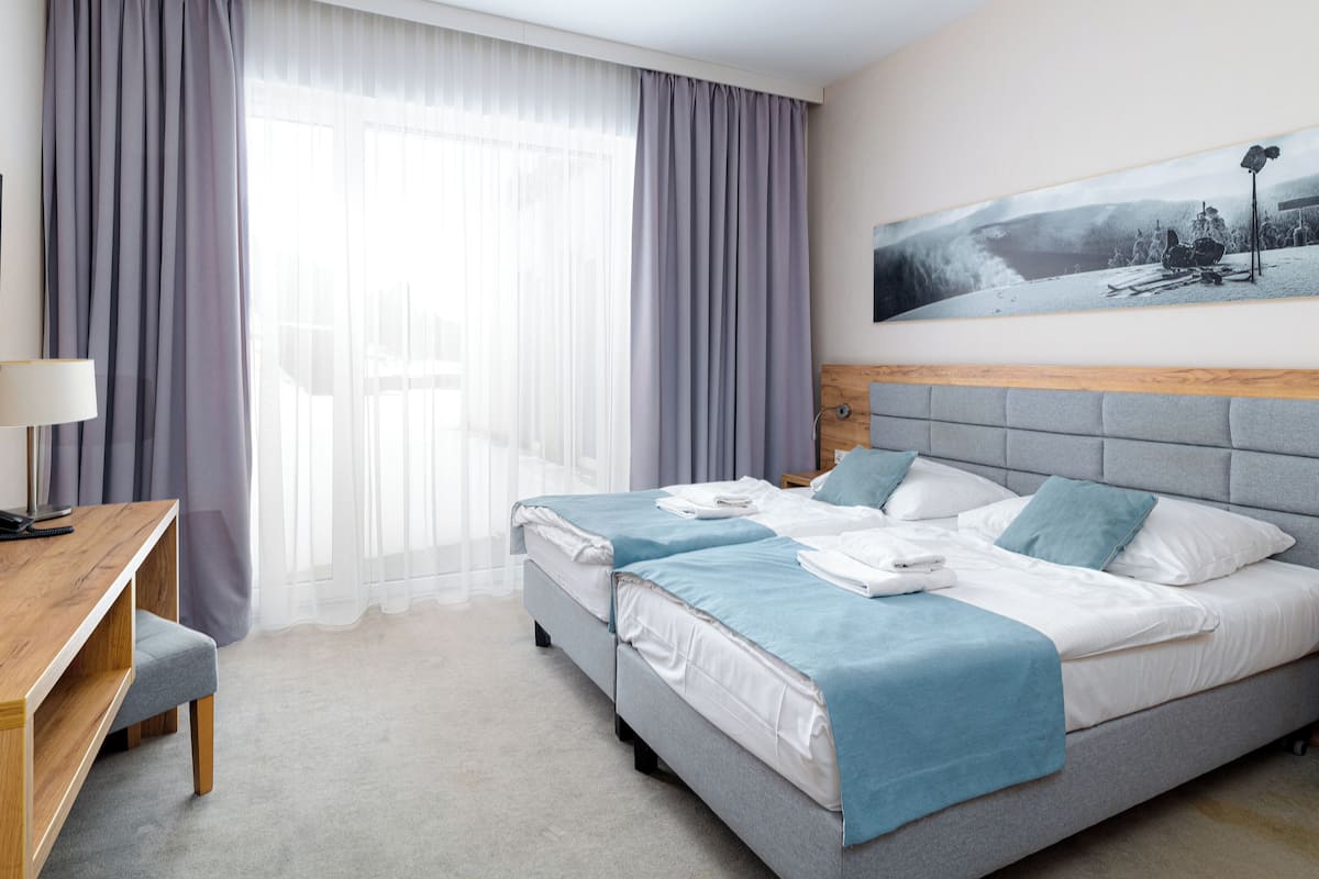 Habitación de hotel con cama, escritorio, silla, televisor y un cuadro en la pared.