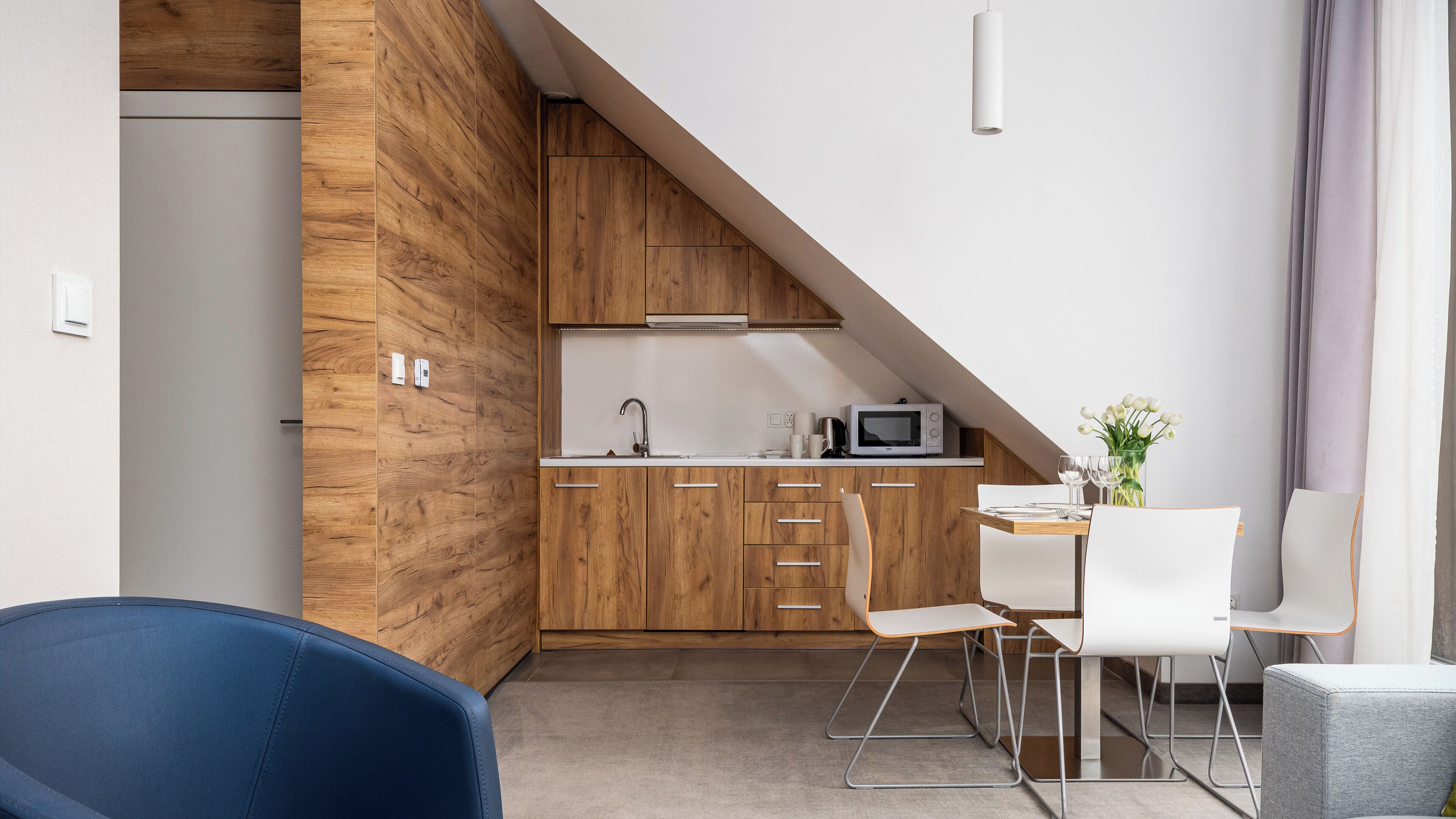 A modern kitchen with wooden cabinets, a microwave, and a dining area with a table and chairs.