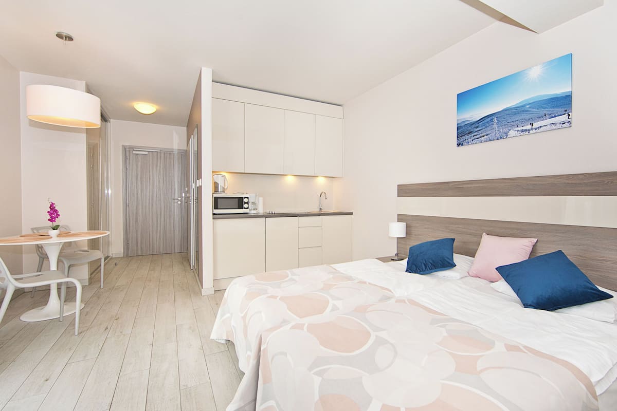 Habitación de hotel con cama, escritorio, silla, microondas y vista a un paisaje nevado.