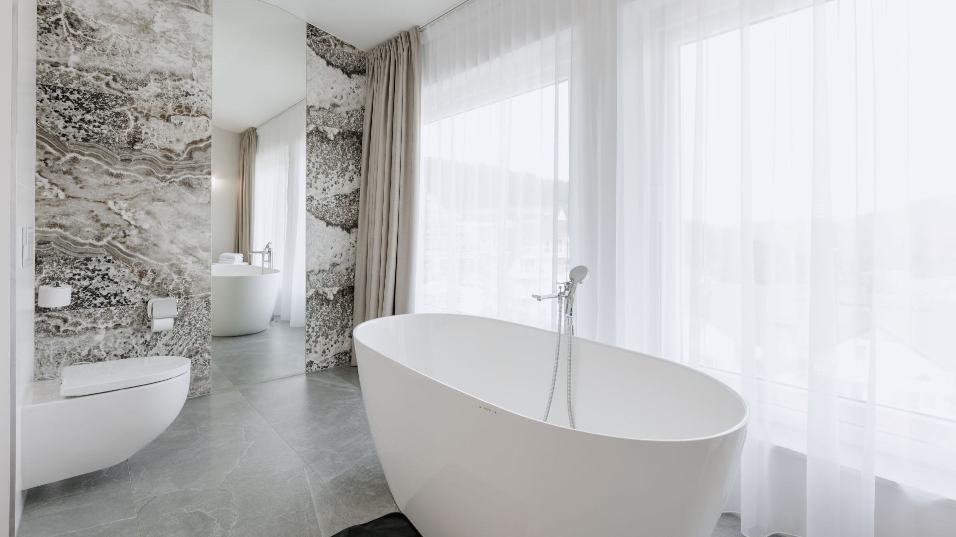 A modern bathroom with a freestanding bathtub, a toilet, and a sink.