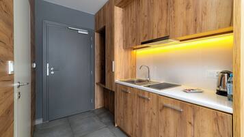 A modern kitchen with wooden cabinets, a stainless steel sink, and a kettle.