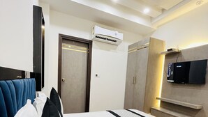 A hotel room with a bed, a TV mounted on the wall, an air conditioning unit, and a ceiling fan. - Hotel Red stone inn New Delhi (New Delhi)