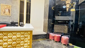 A reception area with a marble reception desk, a large mirror, and a chandelier. - Hotel Red stone inn New Delhi (New Delhi)