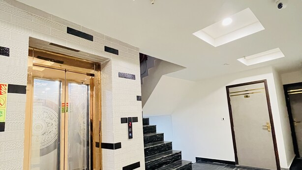 A modern interior with a glass elevator, a staircase, and a clean, tiled floor. - Hotel Red stone inn New Delhi (New Delhi)