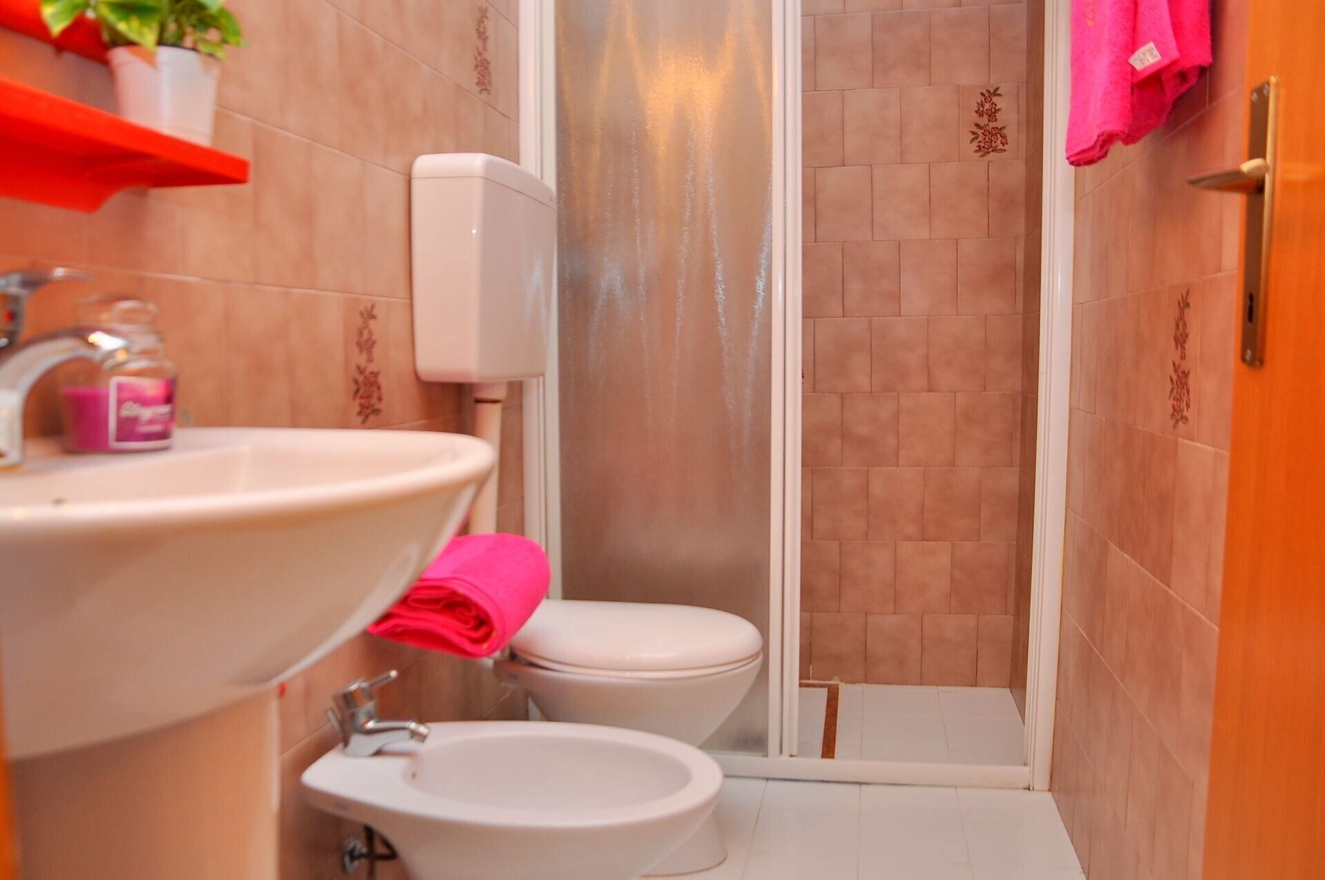 A bathroom with a sink, bidet, toilet, and shower.