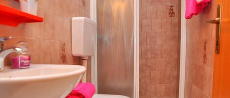 A bathroom with a sink, bidet, toilet, and shower.