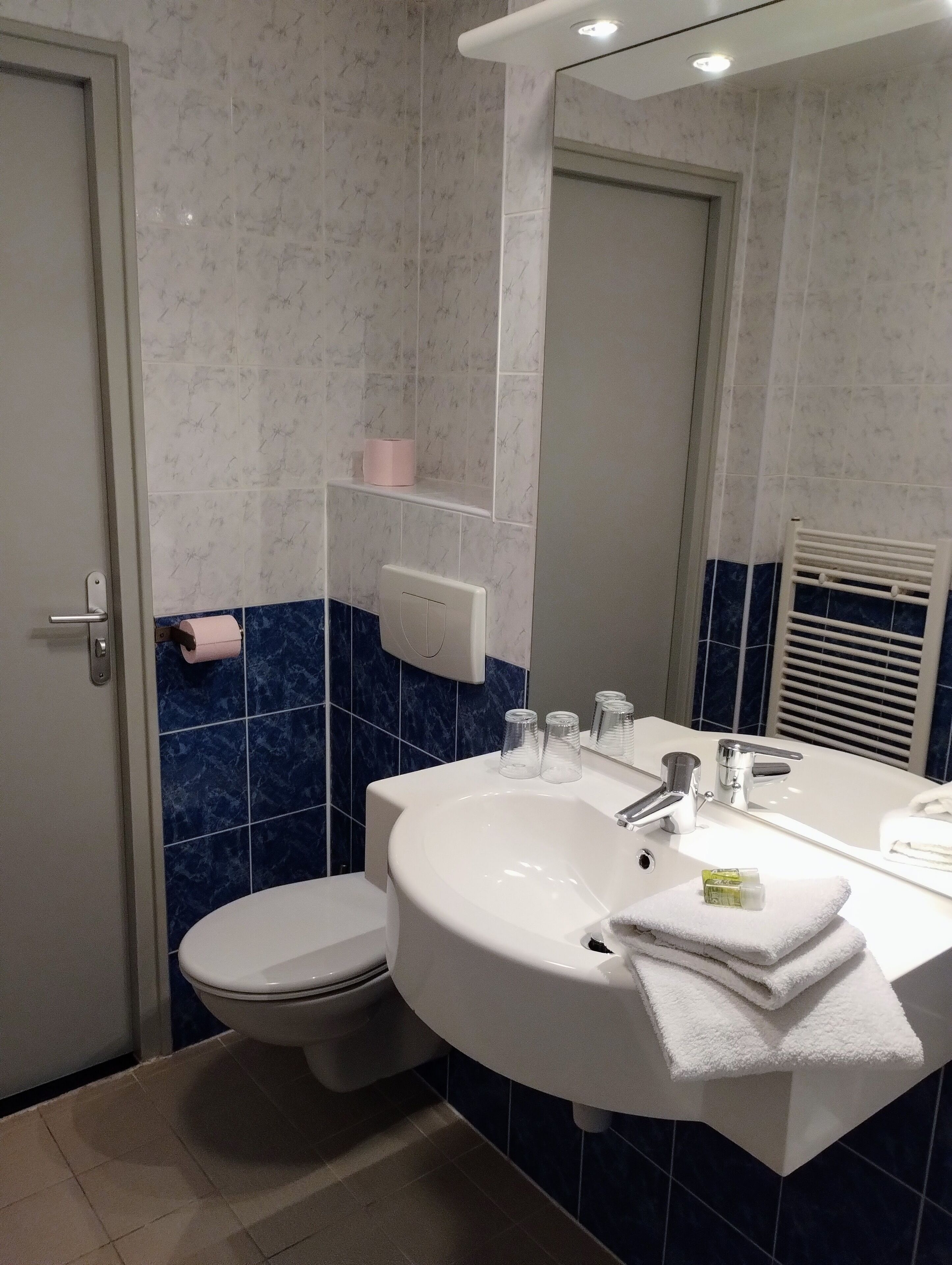 A modern bathroom with a white sink, mirror, and toilet.