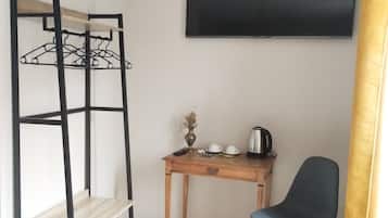 Una habitación con literas, un escritorio con silla, un televisor de pantalla plana y una planta pequeña.