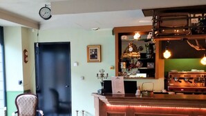 Un espace bar avec un comptoir en bois, un ventilateur de plafond et une horloge au mur.