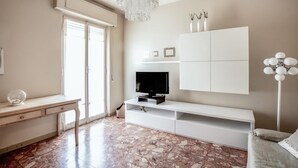 A modern living room with a TV, white cabinets, a desk, and a chandelier. - Amazing apartment in Loano with WiFi (Loano)