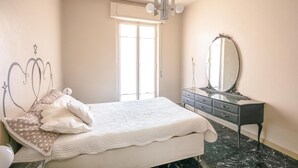 A bedroom with a bed, a dresser, a mirror, and a chandelier. - Amazing apartment in Loano with WiFi (Loano)