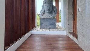 Un edificio moderno con piso de madera que conduce a una gran estatua de Buda.