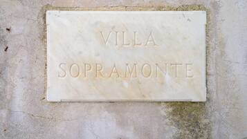 A marble plaque with the inscription "VILLA SOPRAMONTE" on a textured wall.