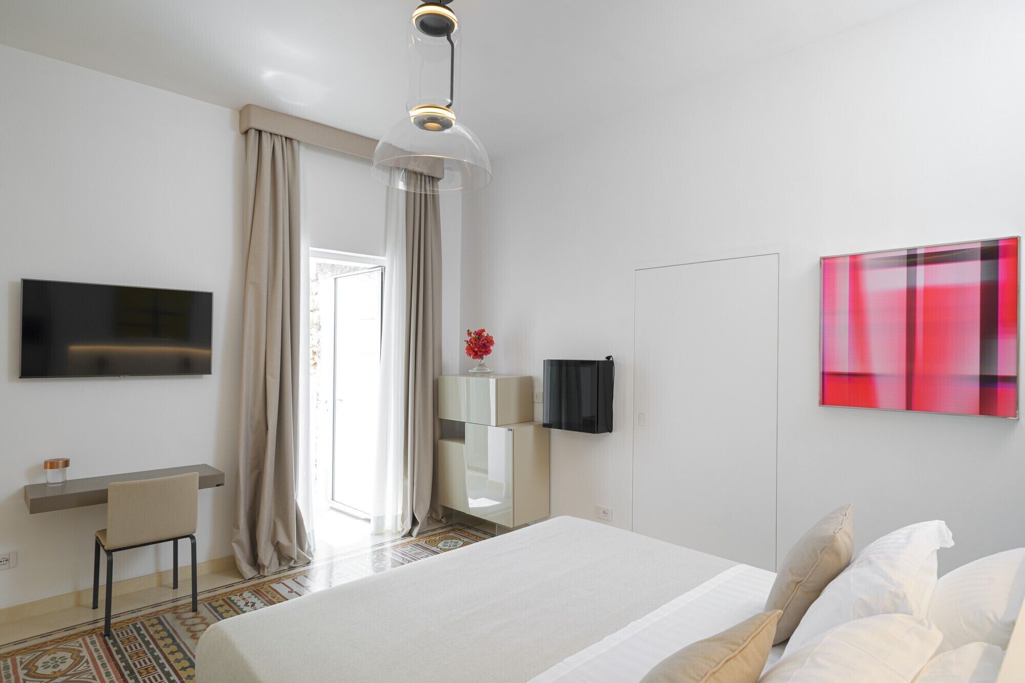 Una habitación de hotel moderna con una cama, un escritorio, un televisor y un cuadro.