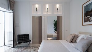 Un dormitorio moderno con una cama grande, una silla, un armario y un cuadro en la pared.