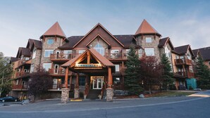 A large, multi-story hotel with a prominent entrance, stone and wood exterior, and multiple balconies. - Three Bears Hydeaway at Stoneridge (Canmore)
