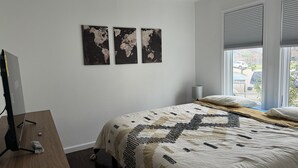 A bedroom with a bed, a desk, a computer, and two world maps on the wall. - Pristine Bungalow in East Austin (Austin)