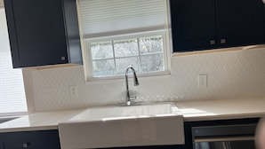A kitchen with a white countertop, a stainless steel sink, and dark cabinets. - Pristine Bungalow in East Austin (Austin)