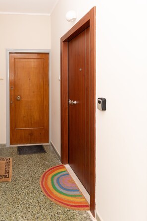 Un couloir avec une porte en bois, un paillasson et un tapis coloré.