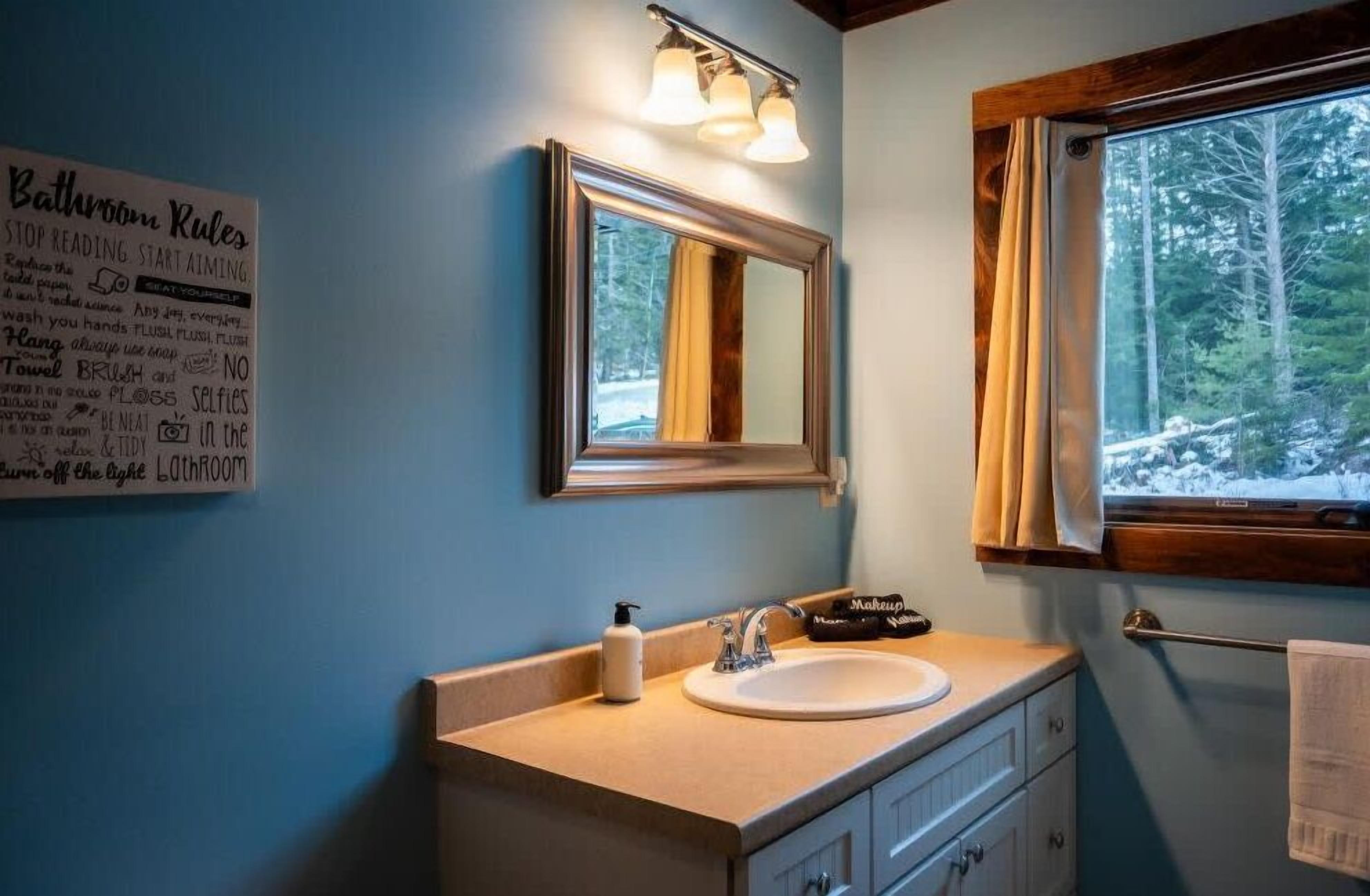 Une salle de bain équipée d’un lavabo, d’un miroir et d’un panneau indiquant les règles à respecter dans les toilettes.