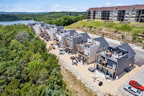 A modern hotel with multiple floors, outdoor seating areas, and a view of a lake. - Majestic Lodge 6BR • Lakeview Retreat w/ Rooftop Deck & Hot Tub • Sleeps 16 (Branson)