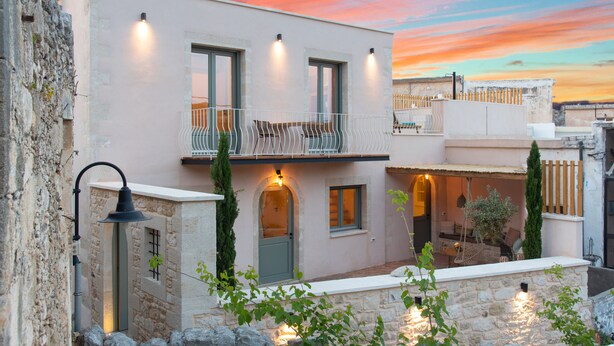 A modern building with a balcony, stone walls, and outdoor seating. - La Mirage Villa (Kournas)