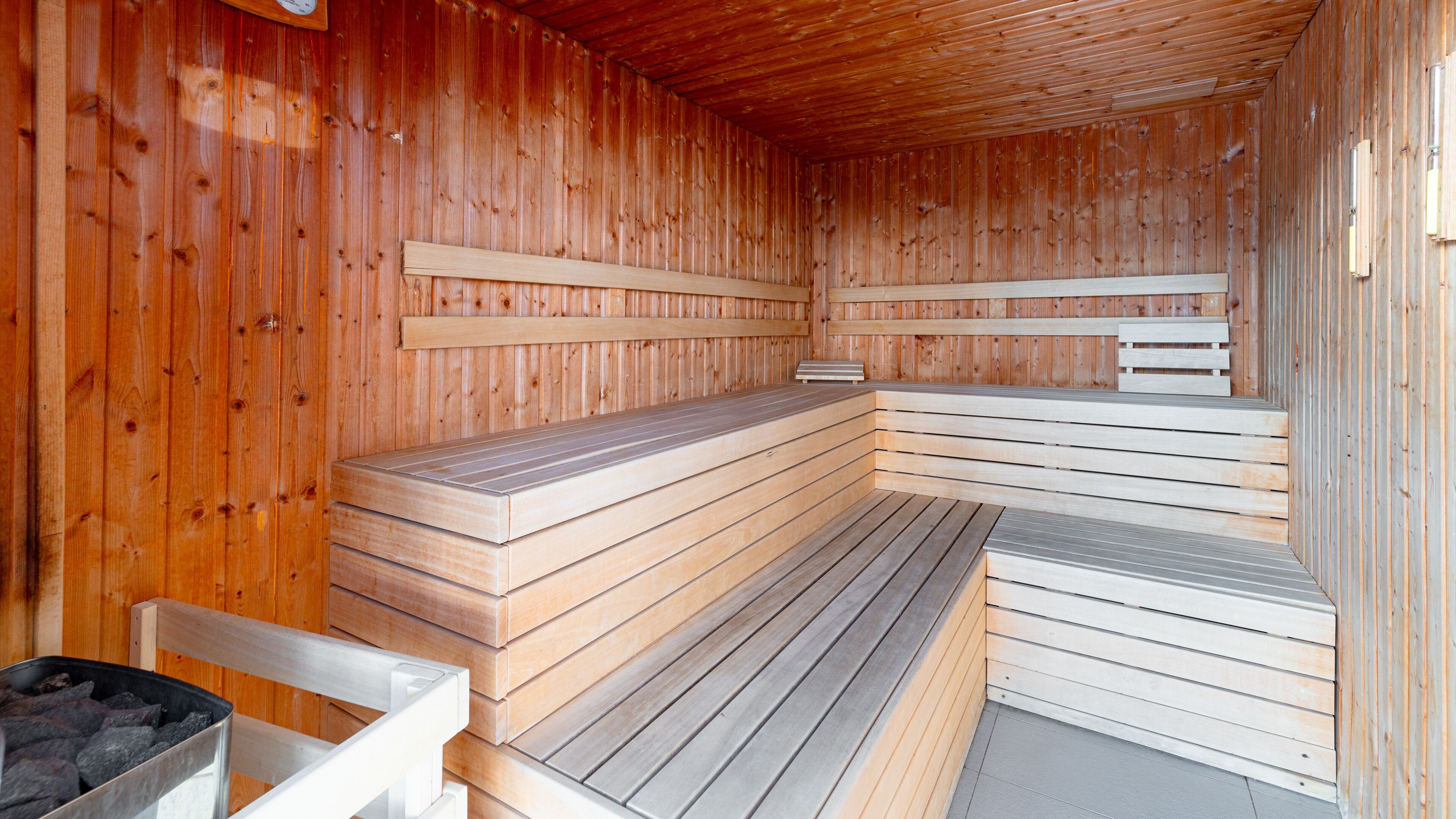 En sauna med træbænke og flisegulv.